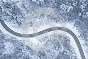 Aerial view of winter road and forest with snow covered trees, top view