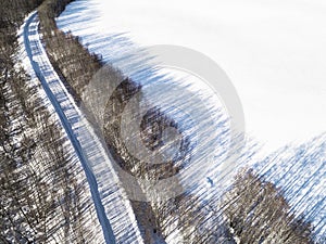 Aerial view of a winter road in the forest. Winter landscape countryside. Aerial photography of snowy forest with road. Captured f