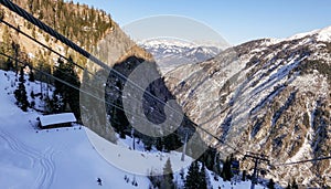 Aerial view of winter slope of Alps with sunny ski pathways and cable road