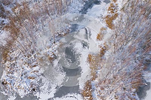 Aerial view of the winter snow covered forest and frozen lake from above captured with a drone