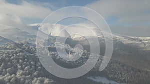Aerial view of winter snow covered mountain peaks and frozen trees, winter footage. Aerial view over winter peaks.