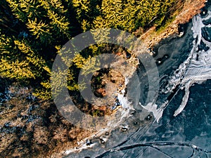 Aerial view of the winter snow forest and frozen lake from above captured with a drone in Finland.