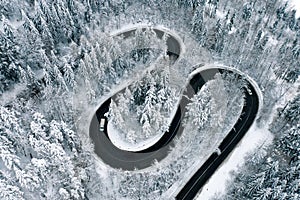Aerial view of a winter winding highway in the middle of the forest