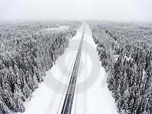 Aerial view at wintry road during snowy storm, highway in northern forest