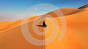 Aerial view of a woman in abaya walking in the desert