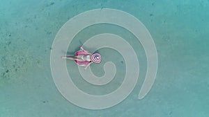 Aerial view with woman in bikini sunbathing as laying on swim ring