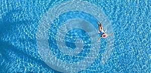 Aerial view with woman in bikini sunbathing as laying on swim ring