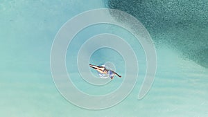 Aerial view with woman in bikini sunbathing as laying on swim ring