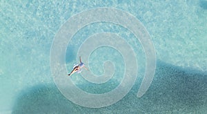 Aerial view with woman in bikini sunbathing as laying on swim ring