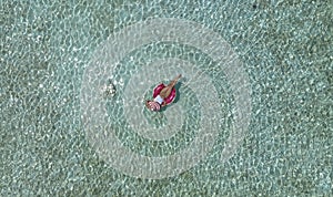 Aerial view with woman in bikini sunbathing as laying on swim ring