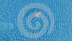 Aerial view with woman in bikini sunbathing as laying on swim ring as blue sea water