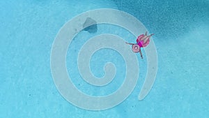 Aerial view with woman in bikini sunbathing as laying on swim ring as blue sea water