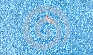 Aerial view with woman in bikini sunbathing as laying on swim ring as blue sea water