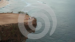 Aerial view of woman exercising on sea shore cliff at sunrise