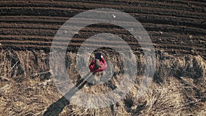 Aerial view of woman farmer with digital tablet computer looks at a fresh plowed field after winter, she makes plans for