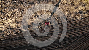 Aerial view of woman farmer with digital tablet computer looks at a fresh plowed field after winter, she makes plans for