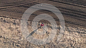 Aerial view of woman farmer with digital tablet computer looks at a fresh plowed field after winter, she makes plans for