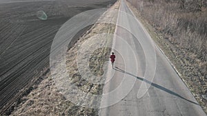 Aerial view of woman farmer with digital tablet computer looks at a fresh plowed field after winter, she makes plans for