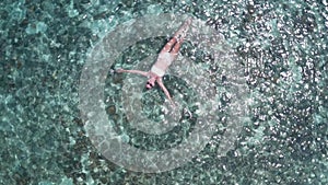 Aerial view of woman floating in crystal clear sea water