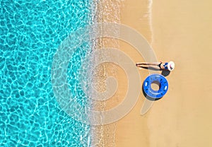 Aerial view of a woman in hat with swim ring on beach and sea