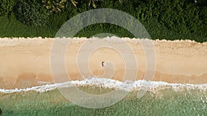 Aerial view of a woman laying on the beach with a surfboard, surfer girl laying on sand in tide down shot. Female surfer