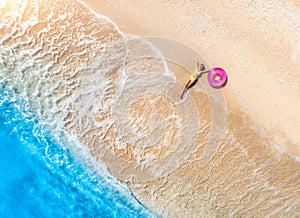 Aerial view of the woman with pink swim ring, sandy beach, sea