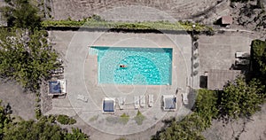 Aerial view of a woman in red swimsuit swimming in the pool. Summer lifestyle