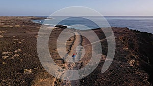 Aerial view of woman runs along the oceanfront nature reserve at sunrise. Healthy active lifestyle