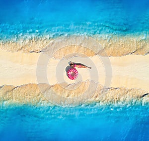 Aerial view of woman on sandy beach with waves on the both sides