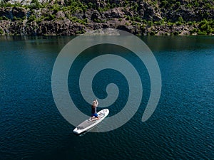 Aerial view on woman on sup board with paddle in the lake