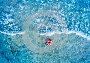 Aerial view of a woman swimming with the pink donut swim ring