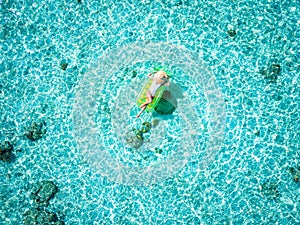 Aerial view of a woman taking a relaxing sunbath on a pinapple shaped float