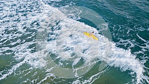aerial view of woman turning over with surfboard in stormy blue sea