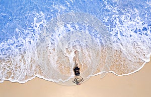 Aerial view, women lounging, sunbathing on the beach and beautiful blue water waves on the island of Thailand