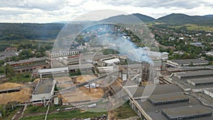 Aerial view of wood processing factory with smoke from production process polluting atmosphere at plant manufacturing