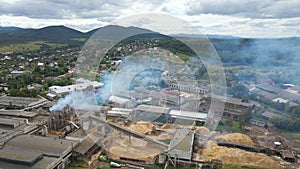 Aerial view of wood processing plant with smokestack from production process polluting environment at factory