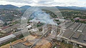 Aerial view of wood processing plant with smokestack from production process polluting environment at factory