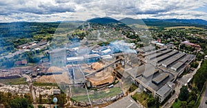 Aerial view of wood processing plant with smokestack from production process polluting environment at factory