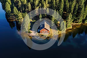 Aerial view of wooden cottage in pine forest by the lake in summer. Generative AI