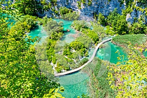 Aerial view of wooden footpath trail at Plitvice lakes, Croatia. Tourist path above blue lagoon near the waterfalls. Empty bridge
