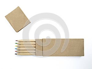 Aerial view of wooden pencils with colored tips in horizontal position and recycled paper case isolated on white. Crayons with eco