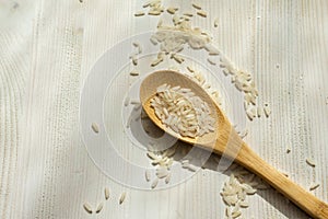 Aerial view of wooden spoon with raw white rice, on white wooden table, horizonta