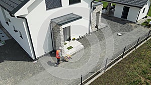 Aerial view of a worker working with a vibrating plate machine in front of house