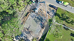 Aerial view of workers at new house construction site pouring concrete of flat slab foundation bedding ready for