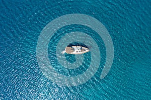 An aerial view of the yacht on the azure sea. Transparent clear water in the Mediterranean Sea. Summer vacations and travels on a