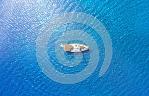 An aerial view of the yacht on the blue sea. Transparent clear water in the sea. Summer vacations and travels on a sailing yacht.