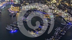 Aerial view on yachts floating in Dubai marina night timelapse. White boats are in canal water.
