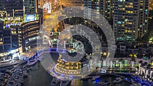 Aerial view on yachts floating in Dubai marina night timelapse. White boats are in canal water.