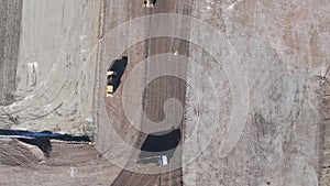 Aerial view of a yellow excavator that is building, a road grader, a heavy soil, a bulldozer that is working on a