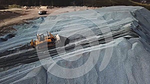 Aerial view of yellow excavator or bulldozer works in sand quarry at the construction site. Stock footage. Industrial